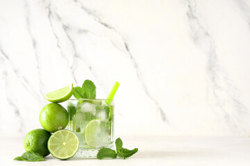 Glass of fresh Mojito cocktail with limes and mint on white background