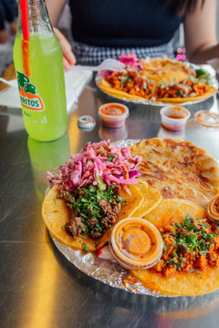 eating plates of tacos, pupusas at Taqueria with bottle of Jarritos lime soda