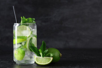 Glass of fresh Mojito cocktail with limes and mint on black background