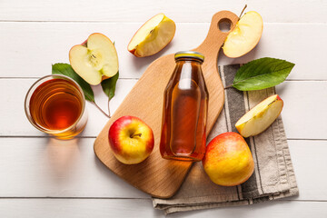 Bottle of fresh apple juice on white wooden background