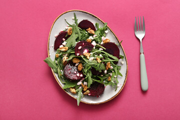 Plate of fresh salad with beet and cottage cheese on pink background
