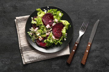 Plate of fresh salad with beet and cottage cheese on black background
