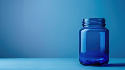 A blue glass jar on a smooth blue surface with a gradient blue background. The jar is empty and positioned to the right of the frame.