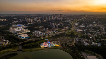 Fototapeta premium Curitiba in Paraná, Brazil. Aerial View. Wonderful sunset with views of buildings and Tanguá Park. Lake with reflection..