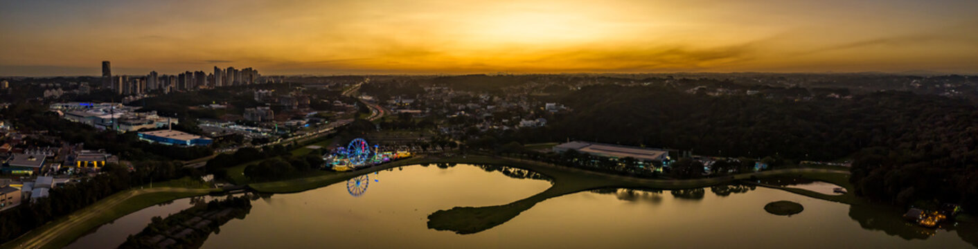 Fototapeta Curitiba in Paraná, Brazil. Aerial View. Wonderful sunset with views of buildings and Tanguá Park. Lake with reflection..