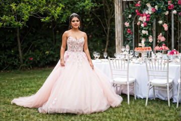 Fototapeta premium a young woman in her quinceanera dress outdoors by the venue tables
