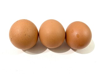 Three fresh and raw chicken brown eggs isolated on white background