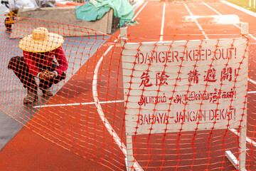 Danger Keep Out signage in multiple language on running track with worker repair in construction site