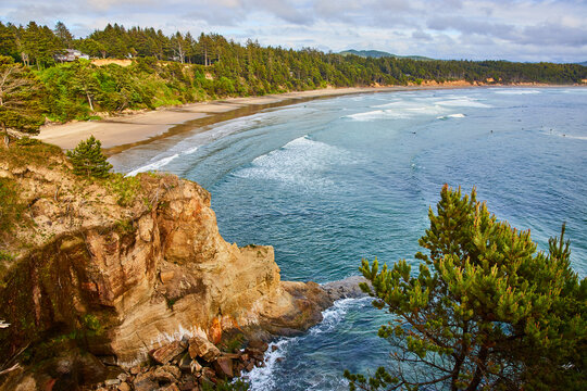 Rugged Cliffs, Forested Coastline, and Surfers from Cliff Vantage