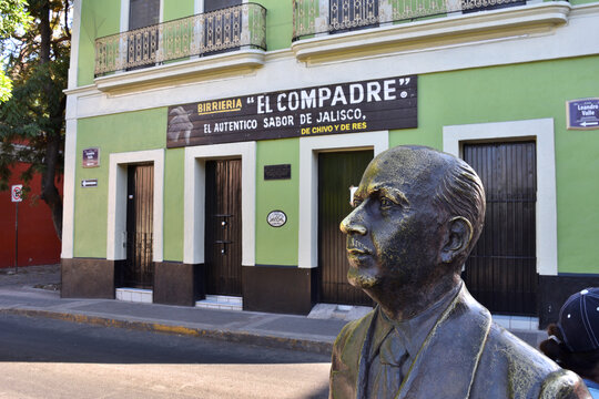 Guadalajara, Mexico - March 18 2024: Cultural Crossroads at Restaurant with a banner that says El Compadre, the authentic flavor of Jalisco, with Francisco Rojas Gonzalez Statue