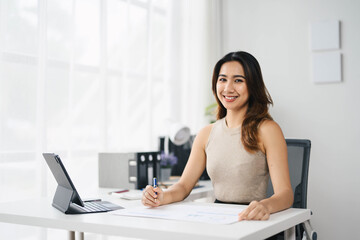 Confident Asian Business Woman Working at Desk in Modern Office with Tablet and Documents