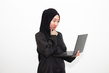 A female office worker wearing a hijab is looking at her work in front of a laptop computer while thinking. isolated in white background