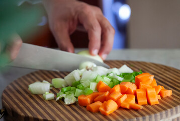 Hands Chopping Mirepoix Ingredients on Wooden Cutting Board. Cooking techniques concept. 