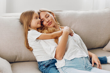 Mother and daughter bonding on a cozy couch against a minimalist white background