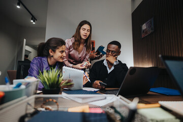 Three colleagues, including men and women, are collaborating on a project in a well-equipped office environment. They focus deeply on discussing and solving business issues.