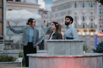 Young business professionals brainstorming ideas and analyzing reports in an outdoor meeting, focusing on marketing, sales, and revenue growth.