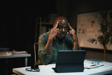 African American Man Working on Laptop at Home Office, Deep in Thought, Nighttime Setting