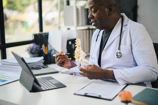 African American Doctor Explaining Spine Model During Online Consultation in Modern Medical Office