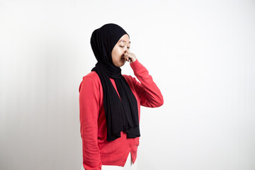 young woman wearing a hijab. wearing a pink sweater. was smelling something smelly and was covering his nose. isolated in white background