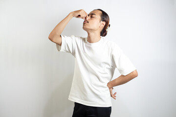 Young Asian man. made a movement covering his nose because of the smell. isolated on white.