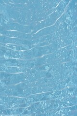 Blue water with ripples on the surface. Defocus blurred transparent blue colored clear calm water surface texture with splashes and bubbles. Water waves with shining pattern texture background.	