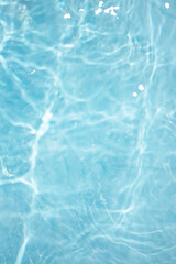 Blue water with ripples on the surface. Defocus blurred transparent blue colored clear calm water surface texture with splashes and bubbles. Water waves with shining pattern texture background.