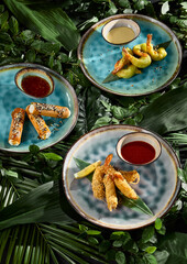 Pan-Asian Appetizer Assortment with Tempura Shrimp and Spring Rolls on Tropical Leaf Background