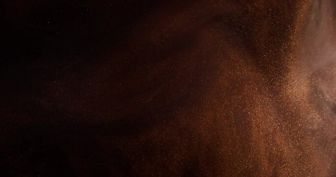 Glitter dust. Smoke splash. Ink water. Blur brown bronze golden color mist sparkling particles texture paint flow on dark black abstract art background.