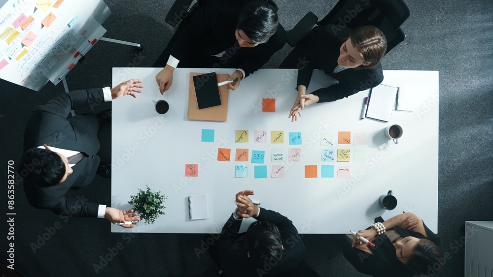 Wall mural Top down aerial view of manager standing and present marketing plan to skilled investor. Diverse business team working together to analyze financial statistic graph at meeting table. Directorate.