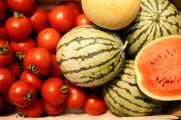 Close up of organic watermelons, melons and tomatoes in a crate.
