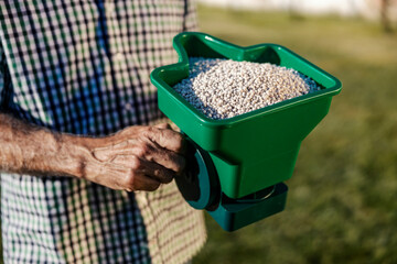 Close up of senior man's hand holding device with fertilizer.