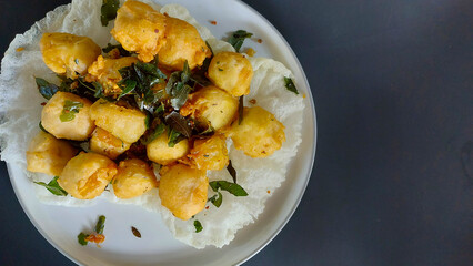 Tahu goreng cripsy, or crispy fried tofu, is one type of snack in Indonesia. With orange leaf on a white plate