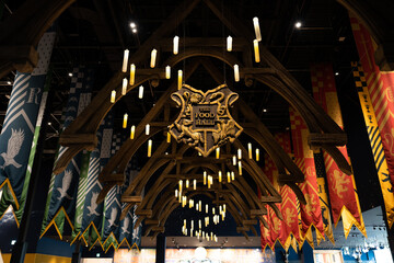 Fototapeta premium JAPAN - Nov 13, 2023: Hogwarts canteen with the food hall logo banner featuring floating candles and Slytherin and Gryffindor flag hanging at Warner Bros Studio Tour Tokyo, The Making of Harry Potter