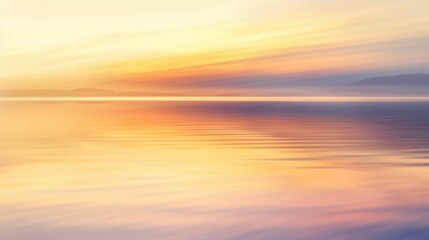 A softly blurred shot of a lake reflecting the colors of a golden-orange sunrise sky, creating a tranquil scene