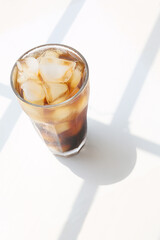 a glass of iced coffee on a white table