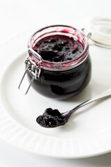 Jar of blueberry jam on white marble table background. Selective focus.