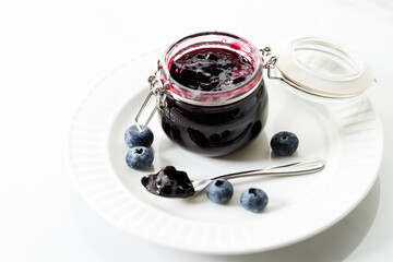 Blueberry jam with fresh berries on white marble table background. Selective focus.