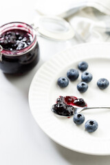 Blueberry jam with fresh berries on white marble table background. Selective focus.