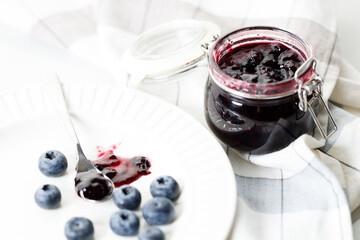 Blueberry jam with fresh berries on white marble table background. Selective focus.
