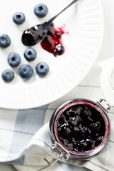 Blueberry jam with fresh berries on white marble table background. Selective focus.