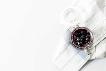 Jar of blueberry jam on white marble table background. Selective focus.