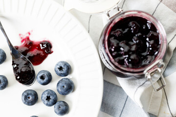 Blueberry jam with fresh berries on white marble table background. Selective focus.