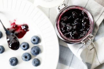Blueberry jam with fresh berries on white marble table background. Selective focus.