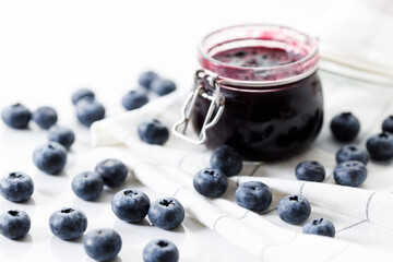 Blueberry jam with fresh berries on white marble table background. Selective focus.