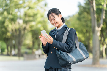 公園でスマホを見る制服姿の女子中学生・女子高校生
