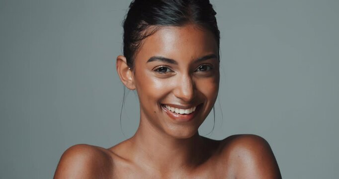 Indian woman, beauty and skincare on studio background with wink and happy face for fun, excited or confidence. Portrait of young model in glow for healthy facial, dermatology and cosmetics or makeup