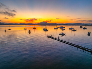 Fototapeta premium Sunrise over the calm water with boats and reflections