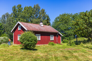 Obraz premium Red old holiday cottage with a garden in the summer