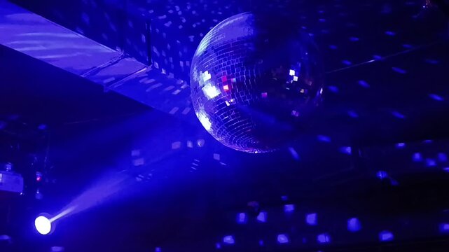 Silver mirror disco ball in the rays of the spotlights