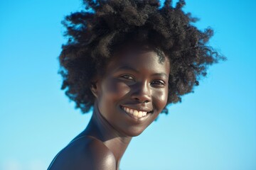 Radiant smile, black woman with beautiful hair against blue sky